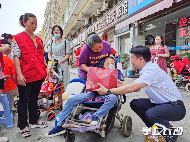 校长谢永红（右）给脑瘫患儿送湖南师大附中教职工子弟同款儿童节礼物。